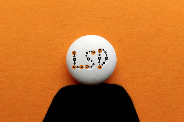 LSD tablet on an orange background in the form of a silhouette of a man with an inscription of multicolored letters stock photo