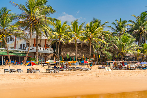 HIKKADUWA, SRI LANKA - JANUARY 22, 2022: Narigama beach at Hikkaduwa with people on sunbeds and small restaurants in background