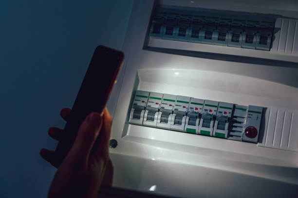 Hand in complete darkness investigate a home fuse box during a power outage. stock photo