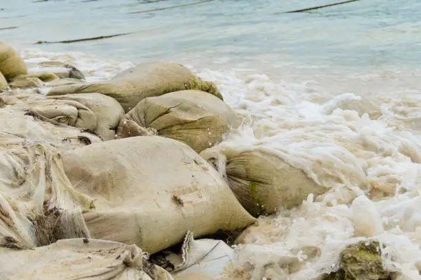 Photo of Sandbag for flood on the sea shore. The waves hit the sandbags, the sea is restless.