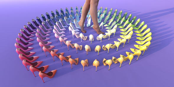 A woman with bare feet and legs standing on tiptoes in the centre of a spiral created from generic high heels stiletto shoes arranged in rainbow colour order against a plain purple background.