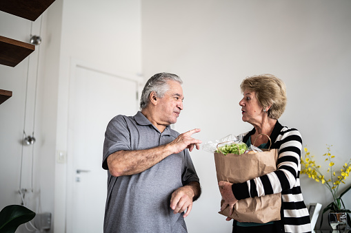Senior couple arriving at home with groceries bag