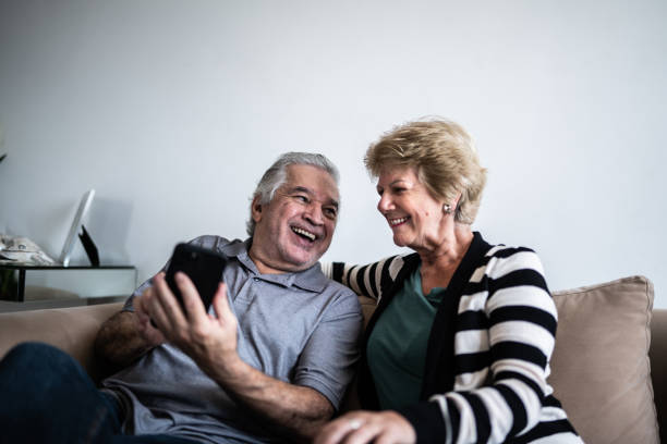 Senior couple using smartphone at home Senior couple using smartphone at home Iphone stock pictures, royalty-free photos & images