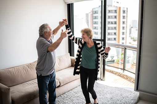 Happy senior couple dancing at home