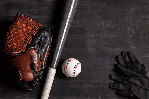 Leather mitt with softball and batting gloves in the outfield