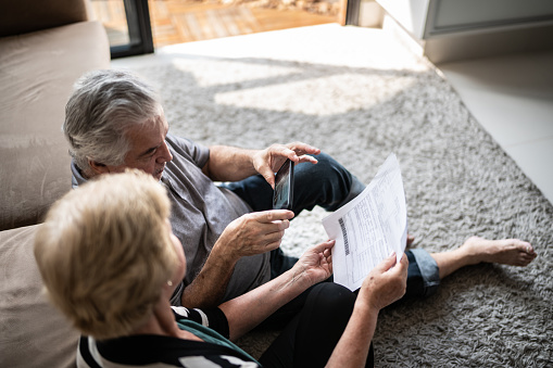 Senior couple paying bills using smartphone at home