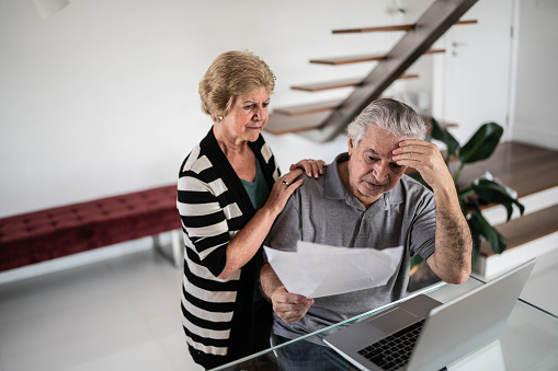 Worried senior couple going through bills at home