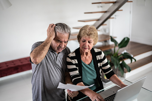 Worried senior couple going through bills at home