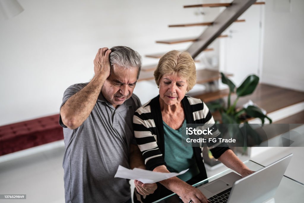 Worried senior couple going through bills at home Struggle Stock Photo