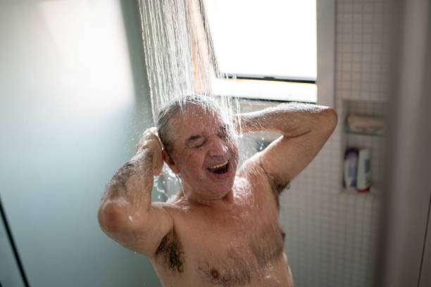 homme âgé heureux prenant une douche à la maison - men naked water male photos et images de collection