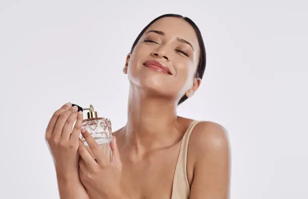 Photo of Studio shot of a young woman spraying herself with perfume