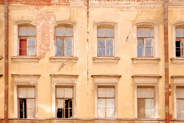 Facade of an old house with broken windows and a crack in the wall