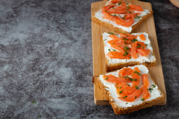 istock Home made bread on a wooden cutting board with curd cheese, salmon and herbs 1376554763