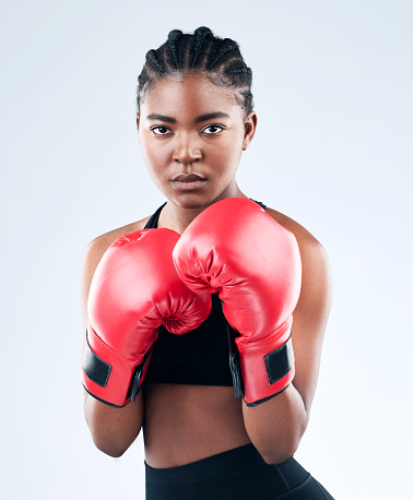 Studio shot of a sporty young woman wearing boxing gloves while posing against a studio background