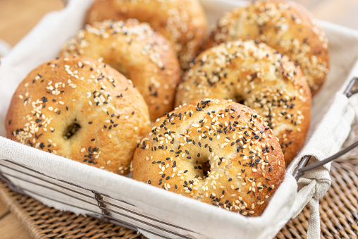 Freshly homemade bagels with sesame seeds on a white canvas covering a metallic basket for brunch sandwiches to garnish