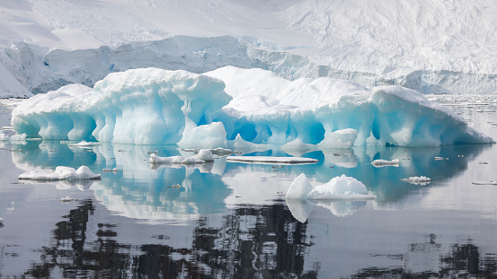Blue iceberg with a mountain landscape backdrop, Antarctic Peninsula.