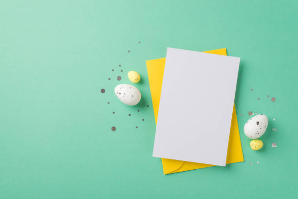 istock Top view photo of easter decorations glowing confetti yellow envelope paper card and easter eggs on isolated pastel green background with blank space 1376601014