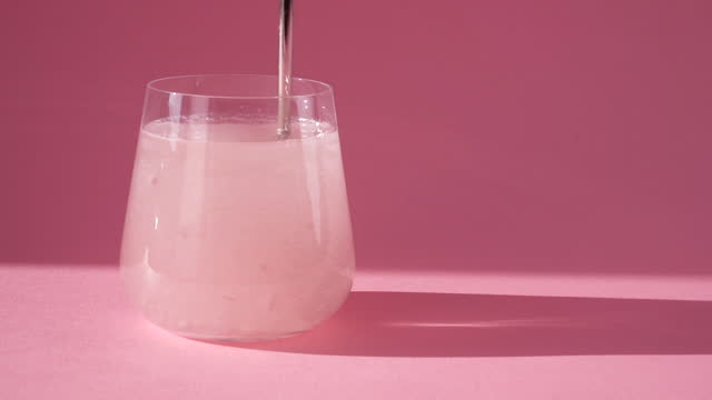 Stirring collagen in a glass of water with a spoon. Skin care. Slow motion