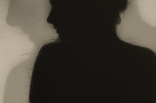 Silhouette of a young beautiful girl behind opaque glass.