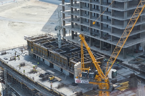 Top view to building construction site with group of builders on roof. Modern skyscraper building construction, residential high-rise project in Abu Dhabi,UAE,March 2022.