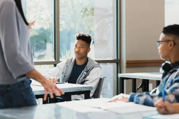 The teenage boy is angry when he is corrected by his unrecognizable mid adult female teacher.