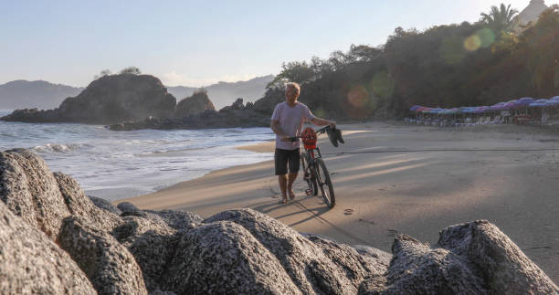 istock Man pushes mountain bike down beach, at sunrise 1376646296