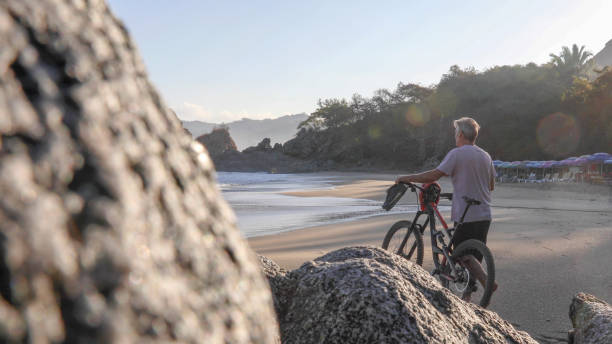istock Man pushes mountain bike down beach, at sunrise 1376646819