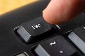 Man pressing the escape key on a simple black office keyboard, finger pushing the esc key button, object macro, extreme closeup, detail. Escaping, stopping, quitting software symbol, simple concept