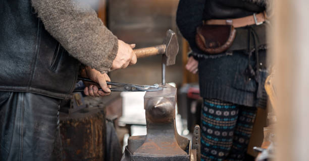 istock An anonymous smith, blacksmith forging a horseshoe hammering, hitting hot metal on an anvil using a hammer, hands closeup, detail, one person. Old jobs, rare occupations, traditional forge detail 1376660445