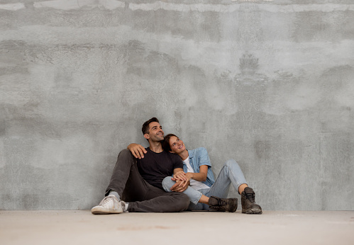 Happy Brazilian couple sitting on the floor thinking about how to decorate their brand new house