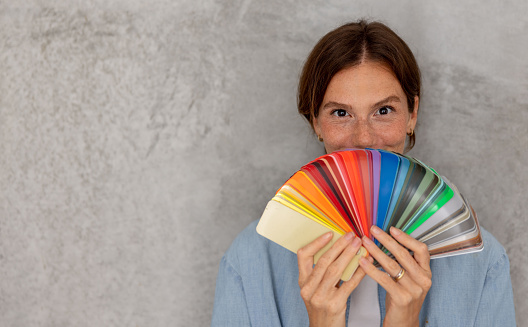 Portrait of a happy Brazilian woman redecorating her house and holding a color swatch