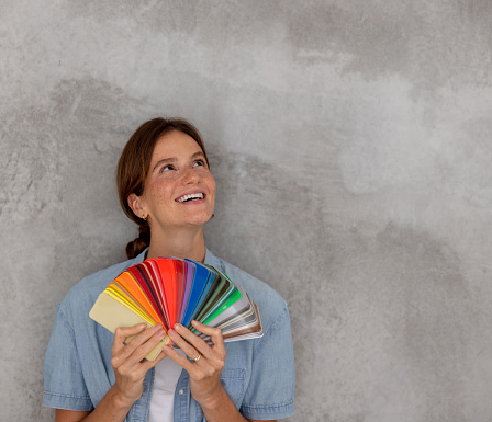 Happy Brazilian woman remodeling her house and thinking about what color to choose for the walls while holding a palette