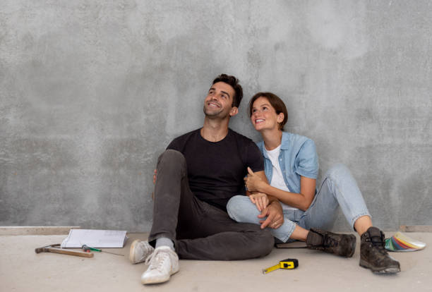 coppia felice che si prende una pausa dalla costruzione della propria casa - sedere per terra foto e immagini stock