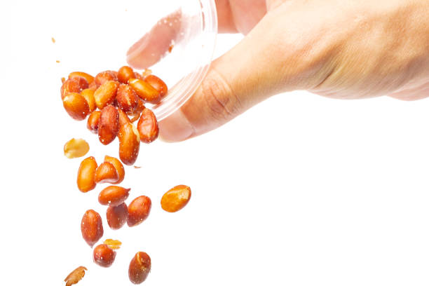 istock Hand pouring peanuts from a bowl, on a white background with copy space. 1376731216