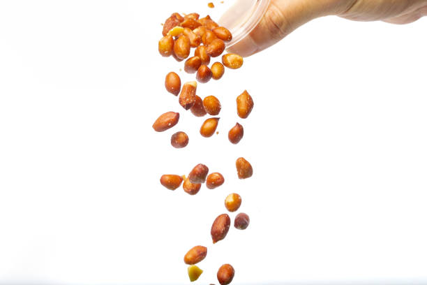 istock Hand pouring peanuts from a bowl, on a white background with copy space. 1376731222
