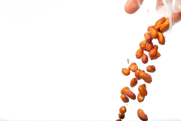 istock Hand pouring peanuts from a bowl, on a white background with copy space. 1376731223