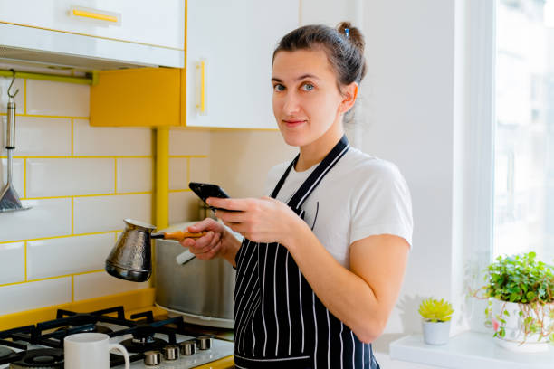 istock woman using smartphone and drinking coffee in kitchen. Concept happy morning leisure 1376778609