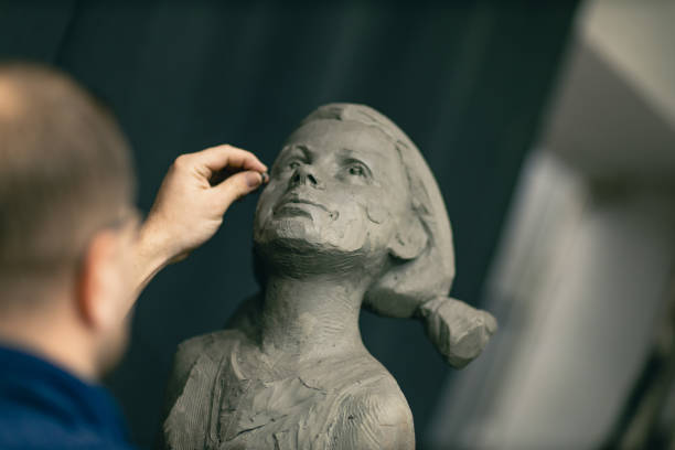 istock Man sculptor creates sculpt bust clay human woman sculpture. Statue craft creation workshop 1376831339