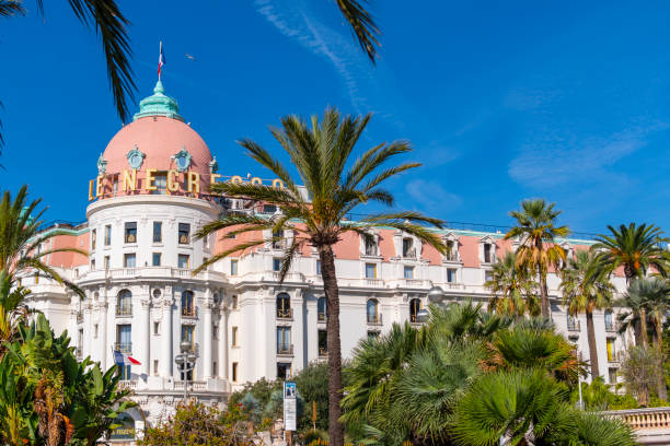 palmen und mediterranes laub umgeben das luxuriöse strandhotel negresco an der promenade des anglais an der riviera von nizza, frankreich. - city of nice france french riviera promenade des anglais stock-fotos und bilder