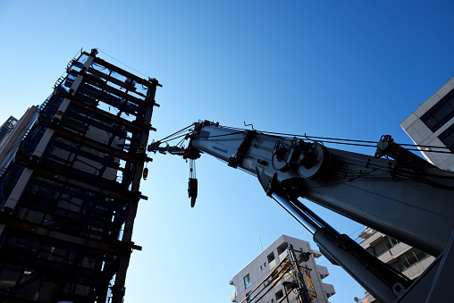 Low angle view of construction site crane and buildings against clear sky.