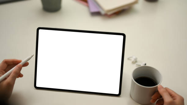 istock Female hands holding stylus pen and coffee cup, looking at tablet screen 1377036401