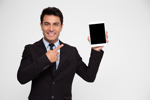 Young business man in suit showing tablet on hand isolated on white background