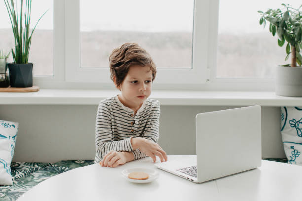 istock Little boy siting at the kitchen and look at the laptop 1377055441