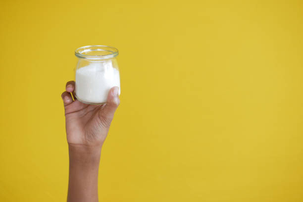 istock holding a jar of white sugar against yellow background 1377055452