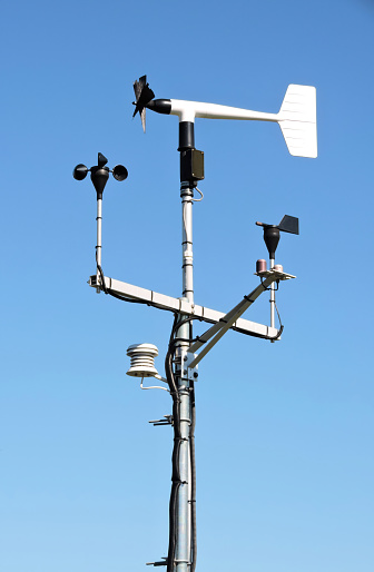 Low angle view of weather equipment on a tall metal pole.