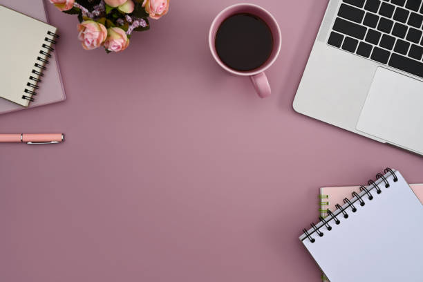 istock Feminine workplace with laptop computer, coffee cup and notebook on pink background. Top view. 1377156787