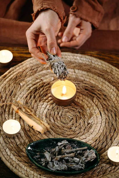 istock Woman hands burning white sage, before ritual on cadle 1377191910