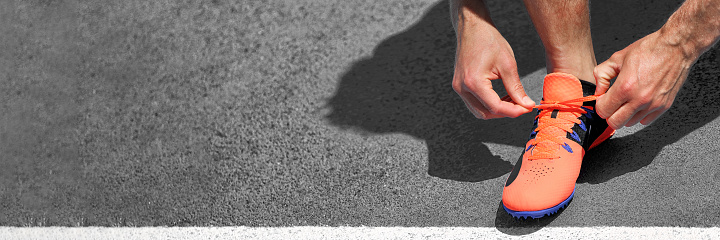 Running track banner crop of athlete runner on starting line ready to start run race competition for success challenge concept. Grey asphalt background panorama.