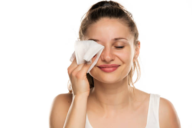 istock A smiling woman cleans makeup from her face with wet wipe 1377264275