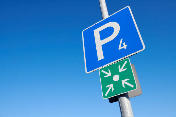 a hexagonal parking sign with a white background, blue border, large blue 'P' on the right, and a black left-pointing arrow on the left, attached to a brick wall.